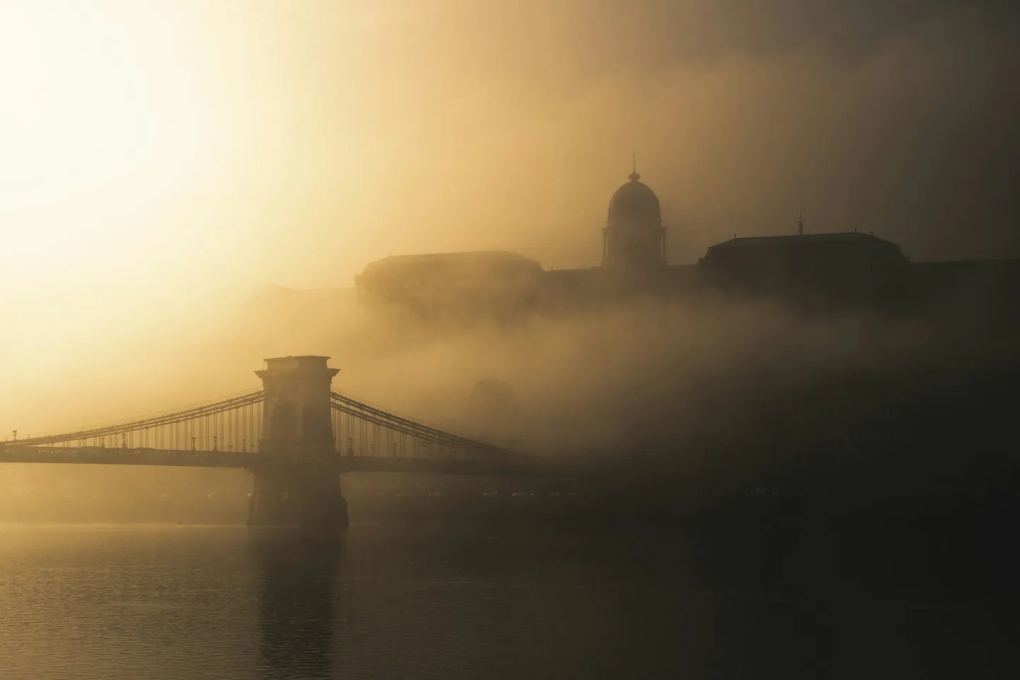 A budapesti Lánchíd és a Budavári Palota párás, aranyló reggeli fényben.